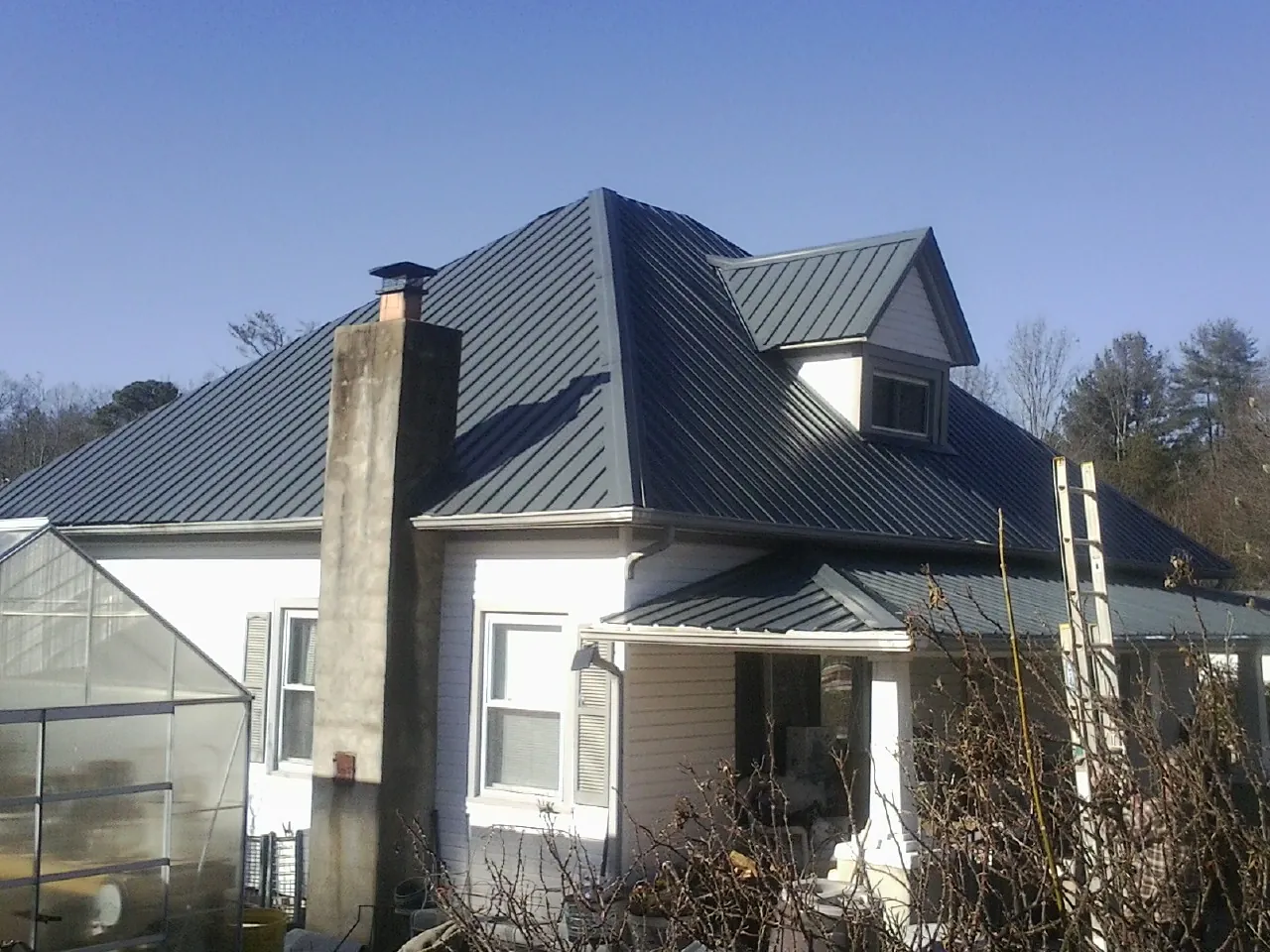 Dark blue standing seam metal roof on a white farmhouse with dormer — Slate & Tile Roof Repair by Roofing Brothers in Mount Angel