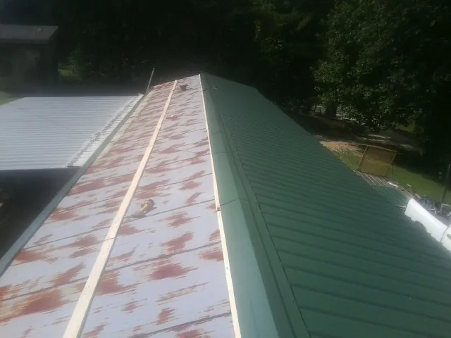 Old rusted panels beside newly installed green metal roofing — Wind Damage Roof Repair by Roofing Brothers in Mount Angel