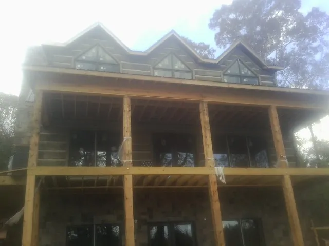 Dormers and porch framing on a large log home under construction — Roof Coating work by our crew in Mount Angel