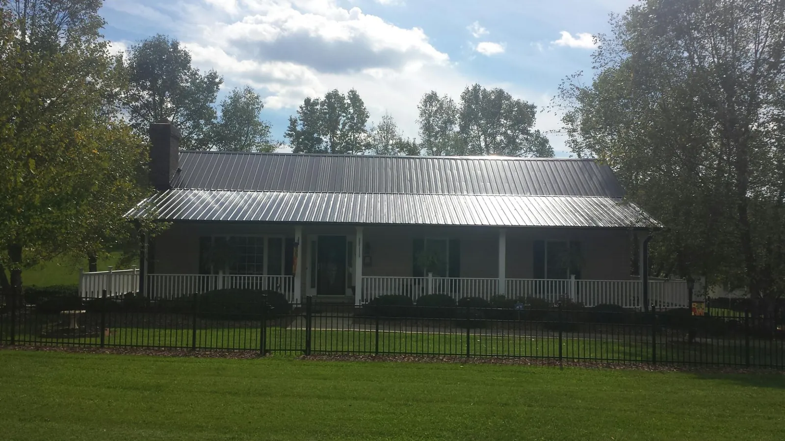 Gray metal roof on a brick ranch with a full width front porch — Gutter Guard Installation work by our crew in Mount Angel