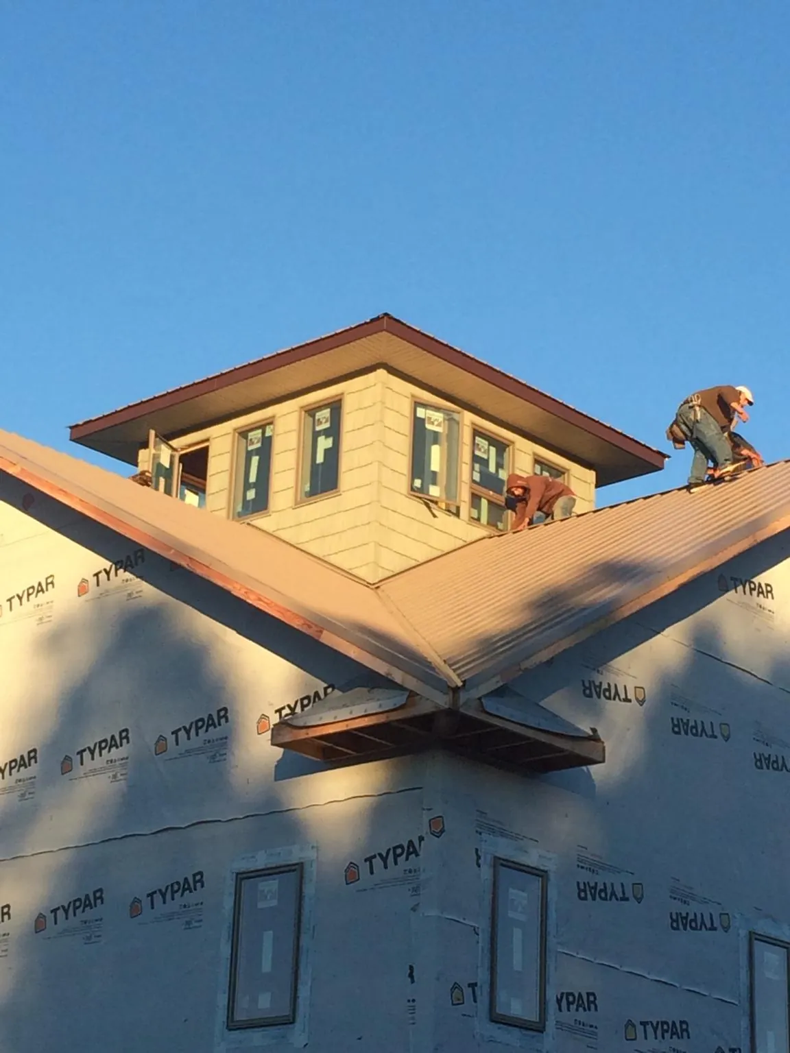Roofers working around a rooftop cupola on a new metal roof at sunset — Roof Waterproofing in Mount Angel by Roofing Brothers
